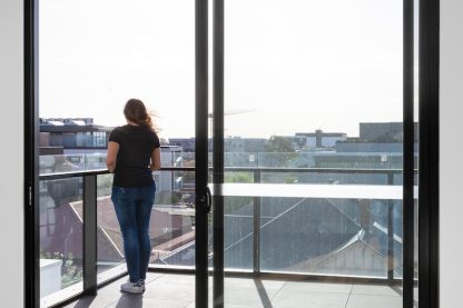 woman in blue denim jeans standing near glass window during daytime