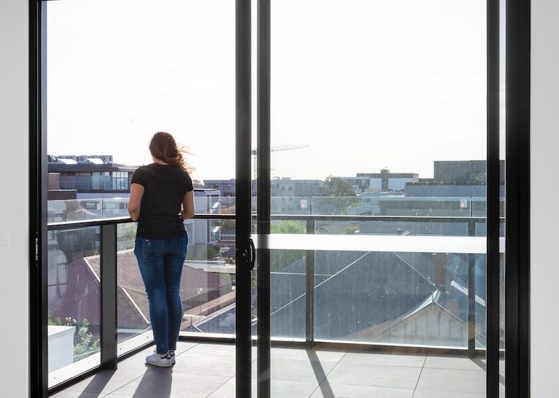 woman in blue denim jeans standing near glass window during daytime